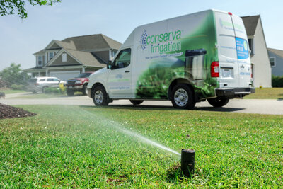 Conserva Irrigation van and sprinkler watering a residential lawn